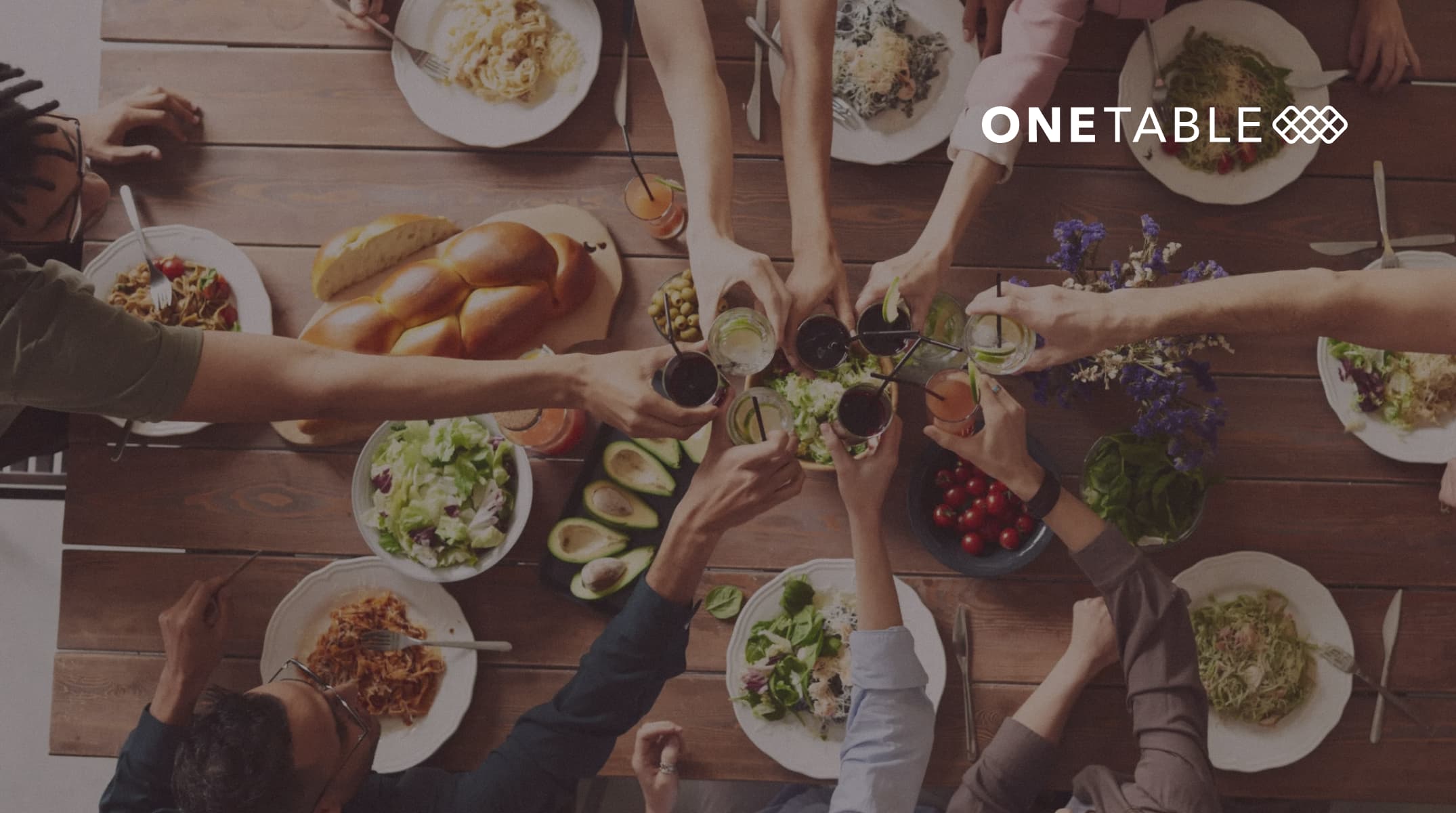 Onetable logo over a group of people raising glasses for a toast at a dinner table
